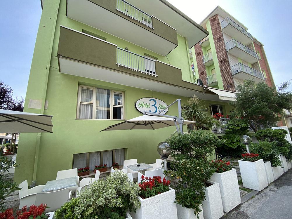 Hotel verde con balconi e fiori, atmosfera accogliente e rilassante.